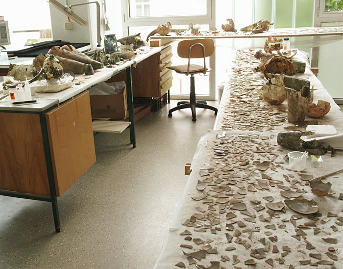 A preliminary sorting of the many finds has taken place. The pieces are sorted by shape, colour, and other features. This makes it possible to identify what may have once belonged together. These are glued together and the first glass vessels re-emerge from the thousands of sherds. © State Office for Heritage Management and Archaeology Saxony-Anhalt, Vera Keil.